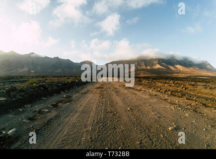 A lungo fuori del terreno su strada strada strada visto dal livello del suolo con le montagne e il blu cielo nuvoloso - viaggi e avventura del concetto di vacanza alternativa e Foto Stock