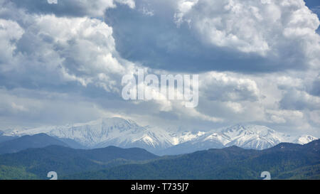 Thunderclouds oltre innevate montagne rocciose Foto Stock