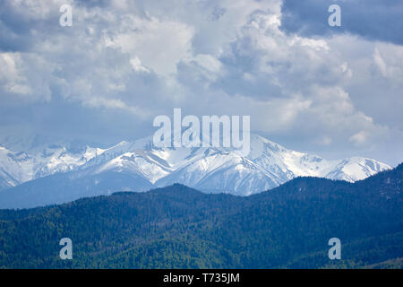 Thunderclouds oltre innevate montagne rocciose Foto Stock