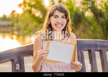 Le donne in uno sfondo tropicale che regge un cartello di carta, mockup Foto Stock