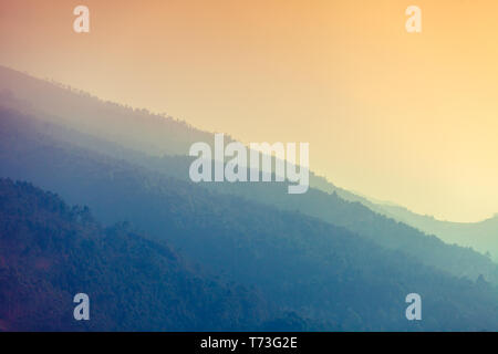 Le gamme della montagna all'inizio mattinata nebbiosa. Sunrise oltre le montagne Foto Stock