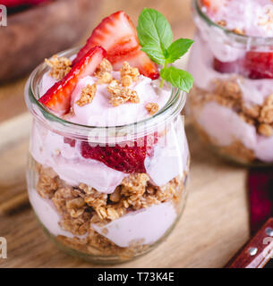 Primo piano di un parfait fatta con yogurt, muesli e fragole fresche in un vasetto di vetro Foto Stock