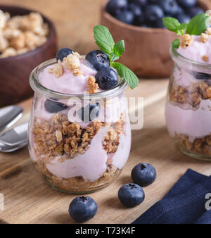 Primo piano di un parfait fatta con yogurt, muesli e mirtilli freschi in un vasetto di vetro Foto Stock