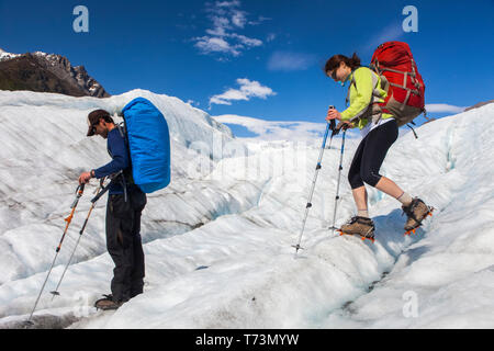 Coppia backpacking attraverso il ghiacciaio Root con ramponi su durante l'estate, Donoho Peak peaking out in background, Wrangell Mountains, Wrangell... Foto Stock