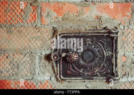Rusty chiuse la porta di metallo in rosso mattone forno di fuliggine Foto Stock