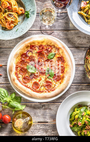 Parte superiore di vista tabella completa dei pasti italiani su piastre e pan. Pizza Pasta risotti e la zuppa di pesce insalata di verdure. Foto Stock