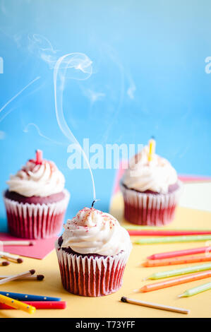 Tre tortini di compleanno con candele blowen fuori e un whisp di fumo su uno sfondo colorato Foto Stock