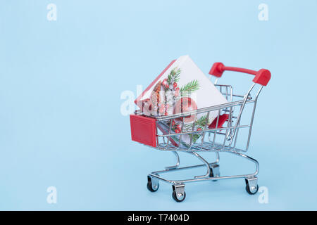 I regali di Natale in un carrello per supermercati su uno sfondo blu con spazio libero per il testo Foto Stock