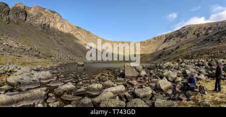 Walkers appoggiato accanto a capre acqua con imponenti balze Dow dietro Foto Stock