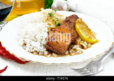 Rosa salmone con il miele, il succo di limone e salsa di soia, riso bollito, fetta di limone e rametto di timo in una piastra, peperoncino, aglio, prezzemolo, igienico e Foto Stock