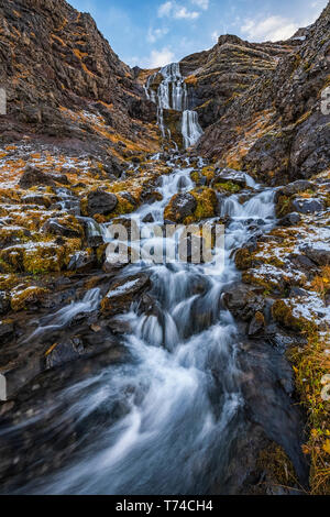 Cascata lungo aspre rocce con licheni e muschi lungo la strada; Islanda Foto Stock