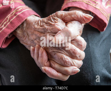 Senior donna di mani giunte in una pensosa riposo; Olympia, Washington, Stati Uniti d'America Foto Stock