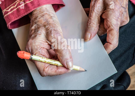 Senior donna di mani pronte per scrivere una nota con una matita; Olympia, Washington, Stati Uniti d'America Foto Stock