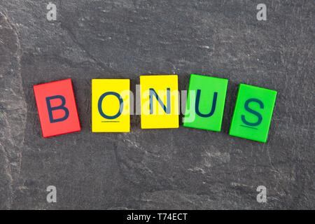 Concetto di Bonus - plastica colorata lettere su sfondo scuro Foto Stock
