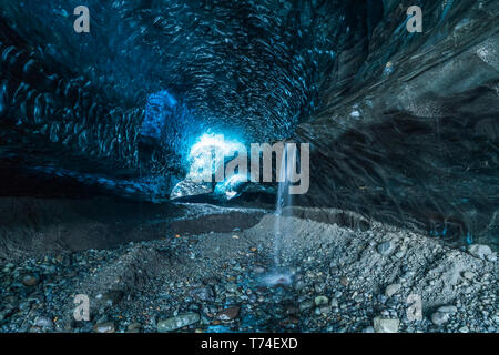 L'ingresso di una grande grotta di ghiaccio nel Vatnajokull calotta di ghiaccio con una cascata; Islanda Foto Stock