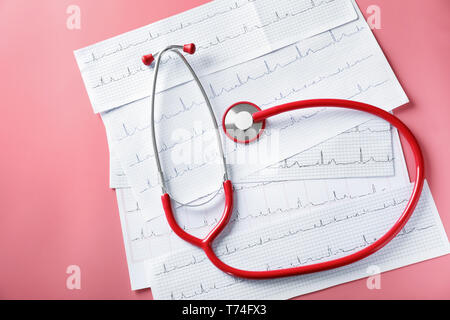 Uno stetoscopio con cardiograms sul colore di sfondo. Health care concept Foto Stock