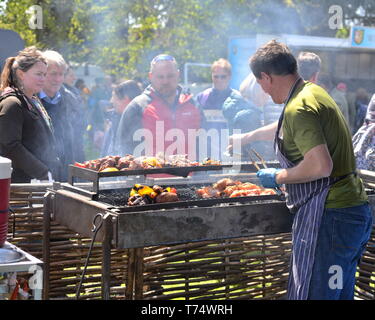 Uomo che serve piatti alla griglia all'aperto presso la Fiera del centro di Cuckoo, vicino a Salisbury, Regno Unito, 4th maggio 2019. L'annuale che si svolge lungo il Borough nel villaggio del South Wiltshire. Foto Stock