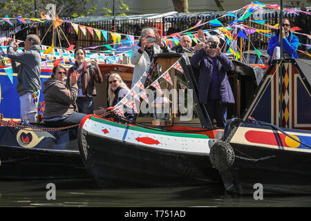 Londra, Regno Unito. Il 4 maggio, 2019. Decorate narrowboats prendere parte all'IWA Canalway cavalcata festival cerimonia di apertura e pageant lungo la canalways e nel bacino, come proprietari gentili tutti onda per partecipanti e spettatori. Le feste popolari sono organizzati per le vie navigabili interne e di associazione verranno eseguiti 4-6Th maggio e che dispongono di più di 100 barche questo anno con canal boat rievocazioni, un accesa sfilata di barche, musica, spettacoli e sport acquatici lungo la piscina e il Grand Union Canal nella piccola Venezia.la piccola Venezia, Londra, Regno Unito, 4 maggio 2019. Credito: Imageplotter/Alamy Live News Foto Stock