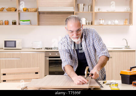 Età contraente repairman lavorando in cucina Foto Stock
