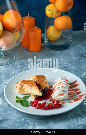 Affettato in casa berry strudel serviti con carni rosse bacche Ribes e zucchero in polvere su un vecchio sfondo su una piastra con gelato pic Foto Stock