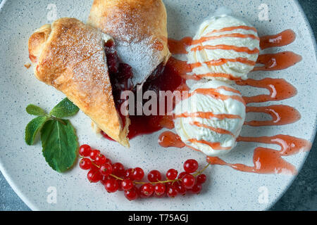 Affettato in casa berry strudel serviti con carni rosse bacche Ribes e zucchero in polvere su un vecchio sfondo su una piastra con gelato pic Foto Stock
