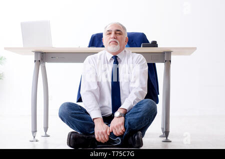 Imprenditore invecchiato facendo esercizi yoga in ufficio Foto Stock