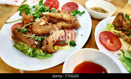 Deliziosi piatti gustosi e croccanti ali di pollo fritte con il piccante impanati pane alle erbe piccanti peperoncino fette di pomodoro insalata verde bella decorazione Foto Stock