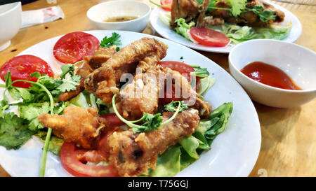 Deliziosi piatti gustosi e croccanti ali di pollo fritte con il piccante impanati pane alle erbe piccanti peperoncino fette di pomodoro insalata verde bella decorazione Foto Stock