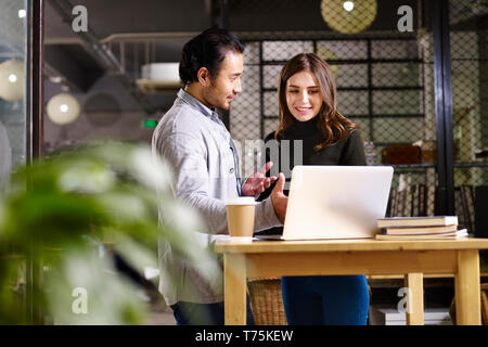 Asian business man e caucasico business donna avente una discussione in ufficio utilizzando il computer portatile. Foto Stock