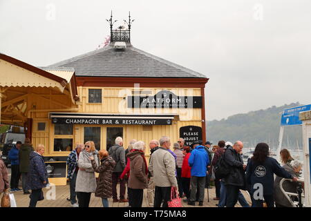 I turisti sono in attesa per il traghetto vicino al binario 1, uno champagne bar & ristorante nel porto di Dartmouth, Devon, Regno Unito Foto Stock