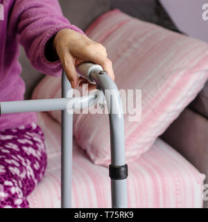 Le mani di una donna senior sulle maniglie di un deambulatore. Azioni di riabilitazione e di assistenza sanitaria concetto. Foto Stock