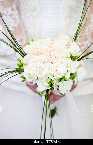 Nozze squisito bouquet di fiori bianchi di rose e fresia nelle mani di un irriconoscibile sposa Foto Stock