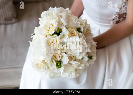 La squisita bridal bouquet di rose bianche e ortensie e fresia nelle mani di un irriconoscibile sposa Foto Stock