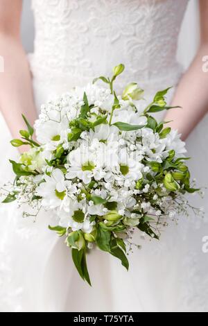 Squisito Bouquet nozze di bianco crisantemi e un ramo di gypsophila, nelle mani di un irriconoscibile sposa Foto Stock