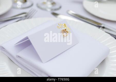 Close up di un vuoto bianco minimalista Luogo di matrimonio card con un ornato oro decorazione di cuore. Foto Stock