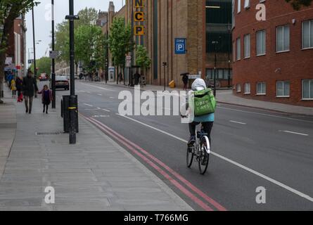 Ciclista garantendo il fast food a Londra. Foto Stock