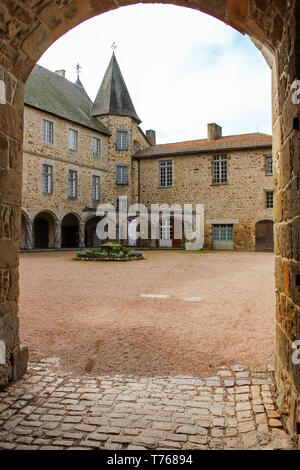 Vista attraverso un arco di pietra per vedere il cortile di un castello. Foto Stock