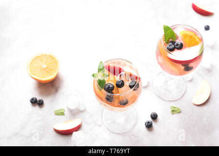 Vino bianco Sangria bevanda con frutta e mirtilli su marmo bianco, copia dello spazio. Vetro a freddo estate bianco ghiacciato sangria cocktail. Foto Stock