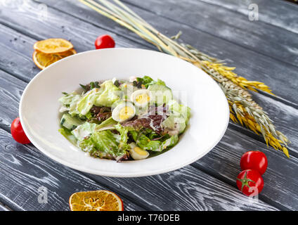 Insalata tiepida con filetto di pollo, cetrioli freschi e funghi sulla tavola con cereali spikelets, pomodorini e arance essiccate Foto Stock