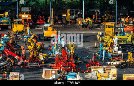 Macchinari pesanti di seconda mano mercato. Gru, carrello, cucchiaio rovescio, e generatore elettrico sporca sul pavimento di cemento. Magazzino di macchinari pesanti Foto Stock