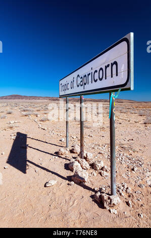 Un segno che segna il Tropico del Capricorno quando esso passa attraverso la Namibia deserto. Foto Stock