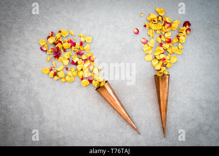 Due vintage coni di rame con il rosso e il giallo dei petali di rosa su sfondo di calcestruzzo. Foto Stock