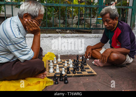 Due uomini seduti sulla strada fuori parco giocando a scacchi Foto Stock
