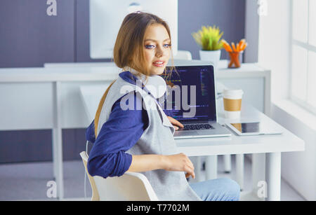 Focalizzato donna attenta nelle cuffie si siede alla scrivania con computer portatile, guarda a schermo, rende note, Impara lingua straniera in internet. Foto Stock