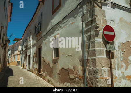 Bianco di vecchie case a schiera con peeling intonaco e nessuna voce cartello stradale a Elvas. Una graziosa città sulla frontiera più orientale del Portogallo. Foto Stock