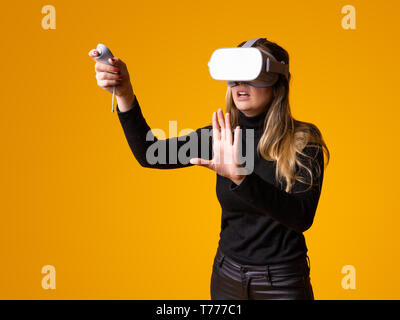 Stupiti giovane donna toccando l'aria durante l'esperienza di VR Foto Stock