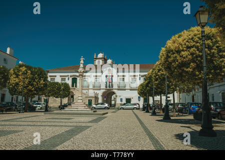 Gogna in marmo in piazza con alberi, pali della luce e il Municipio in background in Campo Maior. Una città medievale con influenze orientali in Portogallo. Foto Stock