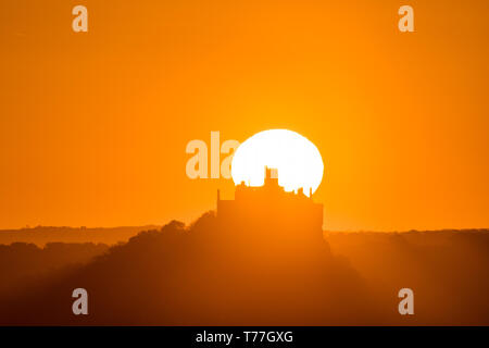 Newlyn, Cornwall, Regno Unito. Il 5 maggio 2019. Regno Unito Meteo. In assenza di vento e una temperatura di 8 gradi al tramonto, il sole è sorto su St Michaels Mount e il mare di Mounts Bay su bank holiday domenica, con la promessa di una bella giornata. Simon credito Maycock / Alamy Live News. Foto Stock