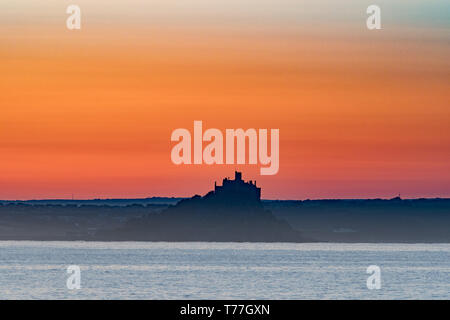 Newlyn, Cornwall, Regno Unito. Il 5 maggio 2019. Regno Unito Meteo. In assenza di vento e una temperatura di 8 gradi al tramonto, il sole è sorto su St Michaels Mount e il mare di Mounts Bay su bank holiday domenica, con la promessa di una bella giornata. Simon credito Maycock / Alamy Live News. Foto Stock