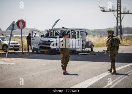 Erez, Israele. 05 Maggio, 2019. Soldati israeliani sostare nelle vicinanze di una vettura che è stata direttamente colpita da un razzo sparato dalla striscia di Gaza sul Kibbutz Erez. Il Primo Ministro israeliano Benjamin Netanyahu domenica ha incaricato l'esercito per aumentare forze attorno alla striscia di Gaza come svasata la violenza nella regione. Credito: Ilia Yefimovich/dpa/Alamy Live News Foto Stock